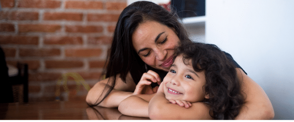Mother embracing child at table.